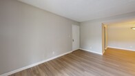 Located at 3390 Fairburn Rd SW in Atlanta, GA, this single-floor unit offers four bedrooms, two bathrooms, and a well-organized layout designed for comfortable everyday living. The interior features a neutral color palette with warm-toned walls, white trim, and textured ceilings throughout. The kitchen is a standout space, outfitted with white shaker cabinetry, granite-style countertops, stainless steel appliances including a refrigerator and range, and light wood-look flooring that extends into the adjacent dining area. The dining room features a pendant light fixture and a closet, adding functionality to the space. The living room is bright and open, with the same light wood-look flooring and access to an outdoor balcony that overlooks lush tree-lined surroundings. The four bedrooms are carpeted and feature large windows that allow natural light to fill each room. The generously sized primary bedroom provides ample space for furnishings. Two closets offer additional storage throughout the unit. The bathrooms are clean and functional, each featuring a tub-shower combination. A connecting hallway ties all rooms together, creating a cohesive and practical flow throughout this well-appointed Atlanta residence.
