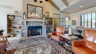 Located in Collierville, Tennessee, the Westbrook Crossing clubhouse is a thoughtfully designed single-floor community space that combines comfort, functionality, and style. The main lounge serves as the heart of the facility, showcasing soaring vaulted ceilings with exposed wooden beam detailing that lend a warm, craftsman-inspired character to the space. A striking floor-to-ceiling stone fireplace anchors the room, flanked by built-in shelving and topped with a rustic wood-framed mirror. Large windows with classic shutters invite generous natural light, while plush seating arrangements layered over patterned area rugs create an inviting atmosphere for gathering and relaxation. Adjacent to the lounge, the kitchen area is outfitted with light blue beadboard cabinetry, stone countertops including a generously curved peninsula, wood-look tile flooring, pendant lighting, and stainless steel appliances including a full-size refrigerator and microwave. A dedicated theater room provides an immersive entertainment experience, featuring rows of cushioned reclining seats, rich wood-trimmed wall paneling, warm sconce lighting, patterned carpet, and a wall-mounted flat-screen display with surrounding speakers. Together, these spaces offer a well-rounded amenity hub suited for both casual socializing and private entertainment.
