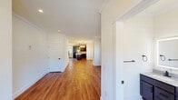 Located at 347 W 5th Ave in Flint, Michigan, this three-bedroom, three-bathroom home spans three floors, offering a well-organized and functional layout. The main level features an open-concept living, dining, and kitchen area. The kitchen is a standout, showcasing rich dark cabinetry, stainless steel appliances, a large center island with a white quartz countertop, pendant lighting, and warm hardwood flooring — a practical and stylish hub for everyday living. The main floor also includes an entrance and additional rooms filled with natural light from large windows fitted with layered sheer blinds. The upper floor hosts the bedrooms, including a generously sized primary bedroom. Bedrooms feature plush carpeting, closets, and windows that bring in natural light. All three bathrooms are finished with a consistent, modern aesthetic: dark vanity cabinetry, granite countertops, backlit mirrors, matte black fixtures, and marble-look tile flooring. One bathroom includes a glass-enclosed shower with wood-accent tile walls. The lower level offers an unfinished basement with concrete walls, wood-framed partitions, and rough-in utilities — providing significant potential for future customization or additional living space.