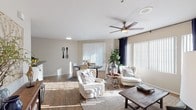 Located at 11875 W McDowell Rd in Avondale, Arizona, this single-story residence offers a well-designed layout that balances comfort and functionality. The living area is bright and welcoming, featuring wood-style flooring, a ceiling fan with light fixture, and large windows with vertical blinds that allow generous natural light to fill the space. The adjoining dining area provides a dedicated space for meals, with sliding door access that brings in additional light and connects to the outdoors.

The galley-style kitchen is equipped with white cabinetry, black appliances including a refrigerator, electric range, microwave, and dishwasher, along with dark countertops and a built-in wine rack, creating a clean and functional workspace.

Two bedrooms each feature plush carpeting, ceiling fans, and large windows dressed with vertical blinds and drapery that offer both light control and privacy. The primary bedroom includes direct outdoor access through a sliding glass door.

Two bathrooms serve the residence, each finished with white cabinetry, dark countertops, and wood-style flooring. One bathroom features a shower-tub combination with a walk-in closet nearby, while the second offers a single-sink vanity with a large mirror. The neutral color palette throughout creates a cohesive and inviting atmosphere.