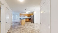 Located at 2600 Beryl Way in Watervliet, NY, this single-floor residence offers a well-organized layout with two bedrooms, two bathrooms, a kitchen, living room, closet, and utility room. The open-concept kitchen is a functional centerpiece, featuring warm oak cabinetry, granite-style countertops, a central island, stainless steel appliances including a dishwasher and refrigerator, and durable wood-look flooring that flows throughout the main living areas. The kitchen connects seamlessly to the living room, which is carpeted and bathed in natural light through large sliding glass doors that open to the outdoors. Both bedrooms are carpeted and feature bright windows with blinds, offering views of the surrounding landscape. The spacious primary bedroom provides a comfortable retreat with ample room for furnishings. The two bathrooms are finished with light tile flooring, oak vanities with granite-topped counters, and clean white fixtures. A dedicated utility room and closet round out the practical offerings of this residence. The overall aesthetic is clean and neutral, with white walls and consistent finishes throughout, creating a bright and move-in-ready environment.