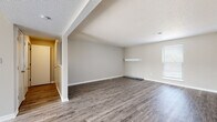 Located at 5604 Floyd St in Overland Park, Kansas, this single-floor residence offers a clean, updated interior with a cohesive neutral color palette throughout. The open living area is a standout feature, showcasing durable grey wood-look flooring, crisp white trim, and a textured ceiling that adds character to the space. Natural light filters in through slatted blinds, creating a bright and welcoming atmosphere. A built-in wall shelf provides a subtle architectural detail in the main living area.

The kitchen is well-appointed with white cabinetry, granite-style countertops, and stainless steel appliances including a Whirlpool electric range with an overhead ventilation hood. The layout is functional and efficient, with ample cabinet storage and counter space. A pass-through opening connects the kitchen to the adjoining living space, enhancing the open flow of the floor plan.

The bedroom features plush wall-to-wall carpeting, a large closet with double doors, and a bright window that brings in natural light. The bathroom is finished with white vanity cabinetry, granite-style countertops, a framed mirror, and a full tub-shower combination, maintaining the home's consistent, updated aesthetic throughout.