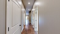 Located at 7901 SW 7th St in Blue Springs, MO, this single-story, 3-bedroom, 2-bathroom home offers a thoughtfully designed layout with quality finishes throughout. The open-concept living room features vaulted ceilings, rich hardwood-style flooring, a ceiling fan, and a sliding glass door that fills the space with natural light and provides direct outdoor access. The kitchen is well-equipped with warm oak cabinetry, granite-look countertops, a tile backsplash, black appliances, and a central island with breakfast bar seating — all complemented by matching hardwood-style flooring. The spacious primary bedroom showcases a tray ceiling with a ceiling fan, plush carpeting, and dual windows that invite natural light. It is accompanied by a dedicated bathroom featuring a walk-in glass-door shower and a vanity with an oil-rubbed bronze faucet. The two additional bedrooms are carpeted and include closet storage and windows overlooking the surroundings. A second full bathroom with a vanity and large mirror serves the remaining bedrooms. A hallway connects all rooms efficiently, rounding out this comfortable and practical single-floor home.