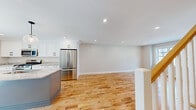 Located at 951 Peverly Hill Rd in Portsmouth, NH, this well-appointed three-floor residence offers 3 bedrooms and 4 bathrooms across a thoughtfully designed layout. Warm hardwood floors flow consistently throughout the main and upper levels, lending a cohesive, inviting character to the home. The main level features an open-concept kitchen and living area, where white shaker cabinetry, stone countertops, stainless steel appliances — including a gas range with over-the-range microwave and French door refrigerator — and recessed lighting come together to create a bright, functional space. A powder room on this level features beadboard wainscoting, a pedestal sink, and marble-look tile flooring. The upper floors house the bedrooms, including a generously sized primary bedroom with ample natural light. The full bathrooms are finished with dual-sink vanities featuring stone countertops, walk-in showers with subway tile surrounds, and marble-look tile flooring. The lower level offers additional living space with light wood flooring and a drop ceiling, providing flexible utility. Throughout the home, neutral tones, clean lines, and recessed lighting create a modern yet welcoming ambiance.