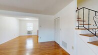 This two-story, two-bedroom, one-bathroom home at 1-186 Nottingham Ct offers a practical and comfortable layout spread across two well-proportioned floors. The main level features a bright, open living room with gleaming hardwood floors and natural light streaming through multiple windows, creating a warm and inviting atmosphere. Adjacent to the living area, the kitchen is equipped with warm-toned wood cabinetry, a center island with counter seating, laminate countertops, and white appliances including a gas range and refrigerator, making it a highly functional space. The ground floor also includes a closet with louvered doors and convenient access to the staircase leading to the upper level. Upstairs, the two bedrooms continue the hardwood flooring theme, each offering clean white walls and ample natural light. The spacious primary bedroom includes a built-in closet, while the second bedroom provides a comfortable and versatile space. A hallway connects the upper-floor rooms. The full bathroom features tile flooring, a tiled tub-shower combination, a wood-cabinet vanity with a white countertop, and a mirrored medicine cabinet, completing the home's functional layout. Throughout, the neutral color palette and consistent hardwood flooring create a cohesive and clean aesthetic.