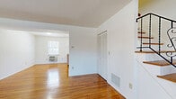 This two-story, two-bedroom, one-bathroom home at 1-186 Nottingham Ct offers a practical and comfortable layout spread across two well-proportioned floors. The main level features a bright, open living room with gleaming hardwood floors and natural light streaming through multiple windows, creating a warm and inviting atmosphere. Adjacent to the living area, the kitchen is equipped with warm-toned wood cabinetry, a center island with counter seating, laminate countertops, and white appliances including a gas range and refrigerator, making it a highly functional space. The ground floor also includes a closet with louvered doors and convenient access to the staircase leading to the upper level. Upstairs, the two bedrooms continue the hardwood flooring theme, each offering clean white walls and ample natural light. The spacious primary bedroom includes a built-in closet, while the second bedroom provides a comfortable and versatile space. A hallway connects the upper-floor rooms. The full bathroom features tile flooring, a tiled tub-shower combination, a wood-cabinet vanity with a white countertop, and a mirrored medicine cabinet, completing the home's functional layout. Throughout, the neutral color palette and consistent hardwood flooring create a cohesive and clean aesthetic.