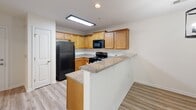 Located at 4103 Cox Pl in Greensboro, NC, this single-floor residence offers a well-designed layout with a thoughtful mix of finishes throughout. The kitchen is a standout feature, showcasing granite countertops, warm honey-toned cabinetry, and a full suite of black appliances including a range, microwave, and dishwasher. A peninsula-style breakfast bar adds both workspace and a casual dining option, while a recessed overhead light illuminates the area. The kitchen flows into adjacent living and dining spaces finished with light-toned luxury vinyl plank flooring, creating a clean and cohesive look. Natural light enters through windows fitted with horizontal blinds, contributing to a bright and airy atmosphere throughout the common areas. The bedrooms are carpeted for comfort and include ceiling fans for year-round climate control, along with windows that bring in additional natural light. A dedicated walk-in closet with wire shelving provides generous storage. The bathroom is elegantly finished with large-format tile flooring, a wood-toned vanity with granite countertops, and a well-lit mirror, creating a clean and functional space. A separate utility/laundry area with wood cabinetry and LVP flooring rounds out this well-appointed residence.
