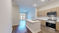 Located at 3260 Clifton Springs Rd in Decatur, GA, this well-appointed 2-bedroom, 2-bathroom unit offers a thoughtfully designed single-level layout. The open-concept kitchen and living area serves as the heart of the home, featuring a central island with a built-in sink, crisp white countertops, light natural wood cabinetry with matte black hardware, and a full suite of stainless steel appliances including a range, over-the-range microwave, and refrigerator. Rich wood-look flooring runs throughout the main living areas, adding warmth and continuity. The living room is highlighted by French doors topped with a transom window, opening to a private balcony with outdoor views—allowing natural light to pour into the space. Both bedrooms are carpeted for comfort, with neutral tones and ample wall space. The spacious primary bedroom includes a double-door closet, providing generous storage. The two bathrooms are finished cleanly in white, with one featuring a full soaking tub and tiled shower surround, and the other offering a walk-in shower unit with built-in shelving. Throughout the unit, clean lines, neutral palettes, and modern finishes create a cohesive and functional living environment.