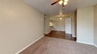 This single-floor residential unit offers a practical and comfortable layout with consistent finishes throughout. The living area features plush neutral-toned carpeting that transitions to wood-style vinyl flooring near the entryway and kitchen, creating a clear distinction between living and functional spaces. A ceiling fan with a light fixture is centrally positioned overhead, and a sliding glass door fitted with vertical blinds allows natural light to fill the room. A built-in counter cutout connects to the kitchen area, adding an open, communicative feel between spaces.

The kitchen is efficiently designed, featuring warm wood-toned cabinetry, light countertops, and black appliances including a coil-burner range, dishwasher, and refrigerator. The wood-style flooring continues throughout this area, complementing the cabinetry tones. A textured ceiling is consistent across the unit.

The bedrooms are generously sized, each equipped with ceiling fans, soft carpeting, and white six-panel doors. One bedroom includes a sliding closet with built-in shelving, while a window provides natural light. The hallway connects the rooms with continued carpeting underfoot.

The bathrooms feature clean, white tub and shower surrounds with built-in shelving niches, offering a functional and well-maintained bathing space. Overall, the unit presents a neutral, move-in-ready environment.