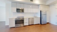 Located on Wilshire Boulevard in the heart of Los Angeles, this efficiently designed one-bedroom, one-bathroom unit offers a clean, modern aesthetic with consistent finishes throughout. Warm-toned wood-look flooring runs continuously across the space, complementing the bright white walls and recessed lighting that keep the interior feeling open and fresh.

The kitchen is outfitted with a full suite of stainless steel appliances, including a range, over-the-range microwave, dishwasher, and refrigerator. Sleek, flat-front white cabinetry extends from counter height to the ceiling, maximizing storage, while a light-toned countertop and simple backsplash complete the contemporary look.

The bedroom is a comfortable, well-proportioned room with a window fitted with horizontal blinds, allowing for natural light and privacy. It connects to a generously sized walk-in closet featuring dual hanging rods and a built-in shelving unit, providing ample and well-organized storage.

The bathroom is finished with large-format, marble-look tile covering both the floor and the full surround of the soaking tub and shower combination, lending a spa-like quality to the space. Chrome fixtures add a polished detail.

The entry hallway provides a welcoming transition into the unit, with a smart thermostat panel and direct access to the kitchen area, keeping the layout logical and functional.