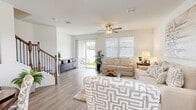 This two-story home offers a thoughtfully designed layout with bright, open spaces and consistent modern finishes throughout. The main living area is generously sized, featuring wood-look flooring, a ceiling fan, and abundant natural light from large windows fitted with white plantation-style blinds. Sliding glass doors provide direct access to the outdoors, enhancing the airy, open feel of the space. The kitchen is outfitted with crisp white cabinetry extending to the ceiling for ample storage, light countertops, a classic subway tile backsplash, and a full suite of stainless steel appliances. The bedrooms are calm and well-lit, each benefiting from large windows with outdoor views, wood-look flooring, and ceiling fans. The primary bedroom is especially spacious, with multiple windows and access to a generous walk-in closet featuring wrap-around shelving and hanging rods on multiple walls. The bathrooms maintain the home's clean aesthetic with white cabinetry, wide vanity mirrors, and warm overhead lighting. A dedicated laundry room provides convenient in-home washing and drying facilities. Throughout, the home presents a cohesive palette of whites and soft neutrals, creating a welcoming and move-in-ready atmosphere.