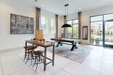 Located at 397 N Central Ave in Hapeville, Georgia, this thoughtfully designed single-floor amenity space offers a dynamic blend of social and relaxation zones within a generously sized open layout. Large-format porcelain tile flooring runs throughout, providing a clean, cohesive foundation that ties the various areas together seamlessly.

The game and entertainment zone is anchored by a full-size pool table beneath a striking pendant light, accompanied by a high-top bar table with industrial-style stools and classic tabletop games. Floor-to-ceiling glass doors open directly to an outdoor pool area, flooding the space with natural light and providing unobstructed views of the surrounding community.

A distinctive wooden slat partition elegantly divides the space, leading to a cozy lounge area featuring a linear fireplace set against an exposed brick accent wall, a plush sectional sofa, and a dark painted ceiling that adds a warm, intimate contrast.

The bar and reception area showcases rich leather wall panels, a patterned tile accent wall, a mounted display screen, and pendant lighting over a sleek countertop with bar seating. An adjacent kitchen island with pendant lighting and a casual dining nook with a round concrete-top table complete the social atmosphere, making this a well-appointed gathering destination.