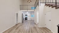 Located at 11231 Otsego St in North Hollywood, Los Angeles, this two-story loft-style residence offers a thoughtfully designed layout across two floors. The main level features an open-concept living, dining, and kitchen area finished with light wood-look flooring that enhances the bright, airy atmosphere. Soaring ceilings in the living room create a dramatic sense of vertical space, complemented by a ceiling fan overhead and a sleek black metal staircase railing that adds a modern industrial touch. The kitchen is well-appointed with white shaker cabinetry, quartz countertops, a marble-style tile backsplash, and a full suite of stainless steel appliances including a gas range, microwave, dishwasher, and refrigerator. A window brings in natural light to the cooking area. The main floor also includes a full bathroom with a glass-enclosed tub and shower combo with clean white tile surround. Upstairs, the loft provides a flexible secondary living or sleeping space with plush carpeting, recessed lighting, and a mirrored sliding-door closet. A second closet offers additional storage. The upper level overlooks the main floor through the open metal railing, reinforcing the home's open and connected feel throughout.
