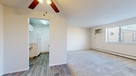 Located at 9235 N Church Dr in Parma Heights, Ohio, this 2-bedroom, 1-bathroom unit offers a practical and efficient single-floor layout. The living area is carpeted and benefits from natural light through a large sliding window, complemented by a wall-mounted air conditioning unit and baseboard heating. A ceiling fan adds to the comfort of the space. The kitchen is efficiently designed with wood-look vinyl flooring, white cabinetry, ample counter space, and a full-size refrigerator, accessed directly from the main living area. The primary bedroom is a well-proportioned carpeted room with a bright window fitted with blinds and baseboard heating. The second bedroom is also carpeted and connects to the hallway, which features hardwood-style flooring and closet access. The full bathroom is outfitted with a vanity with medicine cabinet, tile surround walls, a tub-shower combination, and a classic basket-weave tile floor. A ceiling fan is also present in the bathroom. Throughout the unit, clean white walls and neutral tones create a bright, cohesive atmosphere. Baseboard heating is consistent throughout the rooms, ensuring reliable climate control year-round.