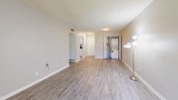 Located at 2845 Palumbo Dr in Lexington, Kentucky, this well-appointed one-bedroom, one-bathroom unit offers a thoughtfully designed single-floor layout that maximizes every square foot of its compact footprint. The living room serves as the heart of the home, featuring smooth light-toned luxury vinyl plank flooring, neutral gray walls, and French doors that open to a private outdoor area, flooding the space with natural light and offering pleasant views of mature surrounding trees. A stacked washer/dryer unit is conveniently tucked within the living area, adding practical functionality. The kitchen is efficiently designed with crisp white shaker-style cabinetry, dark granite-style countertops, a stainless steel sink beneath a window, and full-size black appliances including a refrigerator and dishwasher. The bedroom provides a comfortable retreat with soft wall-to-wall carpeting, neutral tones, a ceiling fan, and its own set of French doors leading to the outdoors. The full bathroom is clean and modern, outfitted with light wood-look LVP flooring, a white vanity with dark countertop, a full tub/shower surround, and a matte black shower rod for a contemporary touch. The overall aesthetic is clean, cohesive, and move-in ready.