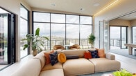 Located at 700 Hamilton Avenue in Nashville, TN, this single-floor amenity space offers a compelling blend of modern interior design and resort-style outdoor living. The interior lounge is anchored by a dramatic wall of floor-to-ceiling black-framed windows that flood the space with natural light and frame sweeping views of the Nashville skyline and surrounding landscape. Warm ambient lighting runs along the ceiling perimeter, complementing the neutral palette of the polished tile floors and crisp white walls. Generous modular sectional seating, accented with rich terracotta, navy, and amber throw pillows, creates an inviting social atmosphere. A built-in media wall with integrated cabinetry adds a sleek, functional element to the lounge area. A billiards table serves as a central entertainment feature, while lush potted greenery enhances the fresh, contemporary feel throughout. Folding glass doors open seamlessly to an expansive outdoor terrace, where large-format tile pavers, a linear fire pit, and a covered pergola structure define distinct zones for relaxation and entertaining. An outdoor kitchen equipped with dual grills, tiled in sage green, provides ample space for al fresco dining. Glass-panel railings along the terrace perimeter preserve unobstructed panoramic views of the Nashville cityscape and rolling hills beyond.