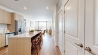 This thoughtfully designed one-bedroom, one-bathroom residence offers a cohesive modern aesthetic throughout its efficiently utilized floor plan. The open-concept kitchen and living area serves as the heart of the home, featuring light wood flat-front cabinetry, stainless steel appliances, a white subway tile backsplash, and granite countertops that extend to a central island with bar seating — ideal for both cooking and casual dining. Warm hardwood-style flooring flows seamlessly through the entire unit, complementing the bright, neutral palette of the walls and trim.

The living area is generously proportioned, benefiting from a large window that invites natural light and provides outdoor views. The bedroom is a comfortable retreat with its own window, ceiling fan, and direct access to the full bathroom. The bathroom features a granite-topped floating vanity, a full soaking tub with shower, and matching hardwood-style flooring that maintains visual continuity.

Storage is a standout feature of this residence, with four closets including a spacious walk-in closet outfitted with wire shelving and hanging rods. A dedicated laundry area and a well-connected hallway round out the practical layout, making this a highly functional and stylish living space.