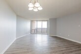 Located on Rathburn Road East in Mississauga, Ontario, this 1-bedroom, 1-bathroom unit offers a practical and comfortable layout across a single floor. Upon entry, a hallway with a large sliding-door closet provides generous storage and leads into the main living areas. The combined kitchen and living room forms the heart of the unit. The kitchen is outfitted with white cabinetry, ample upper and lower storage, a double sink with countertop workspace, and full-sized white appliances including an electric range and refrigerator, all set on clean light tile flooring. The living room is bright and airy, featuring light hardwood-style flooring, soft neutral walls, a tasteful chandelier, and a large window that fills the space with natural light. A sliding glass door opens onto a private balcony, extending the living space outdoors. The bedroom is a comfortable size, finished with rich wood-tone laminate flooring, neutral grey walls, and a window offering pleasant outdoor views. The bathroom is clean and functional, featuring a full soaker tub with a tiled surround and handheld showerhead, a vanity with sink, and tile flooring throughout. Textured ceilings are consistent throughout the unit, adding a classic character to this well-maintained Mississauga residence.