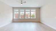 Located at 462 Cherry Street in downtown Macon, GA, this single-floor, three-bedroom, two-bathroom unit offers a well-designed layout with modern finishes throughout. Light hardwood-style flooring runs continuously across the entire space, creating a cohesive and airy feel.

The open-concept kitchen and living area serves as the heart of the unit. The kitchen is outfitted with gray shaker-style cabinetry, granite countertops, stainless steel appliances including a range and refrigerator, and a central island with pendant lighting overhead — ideal for both cooking and entertaining. The adjoining living area is generously sized and features a large bank of windows that flood the space with natural light and offer views of the surrounding neighborhood.

The primary bedroom is a spacious retreat, while the two additional bedrooms are well-proportioned, each with a ceiling fan and windows for natural light. One bedroom includes a sliding-door closet, and a dedicated walk-in closet with wire shelving provides ample storage. 

The unit also includes an in-unit laundry room with a full-size washer and dryer. Clean white walls, modern panel doors, and consistent trim details contribute to a fresh, contemporary aesthetic throughout. A well-connected hallway links all rooms efficiently, completing this functional and attractive layout.