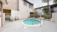 Located at 8382 Whitaker St in Buena Park, California, this residential community presents a well-maintained, multi-building complex designed for comfortable communal living in Southern California. The architecture features stucco exteriors with wood-accented detailing, low-pitched rooflines, and diagonal wood paneling that lend the buildings a classic California-contemporary character.

The outdoor common areas are a central highlight of the property. A sparkling swimming pool is accessible through a gated entry, surrounded by a generous concrete deck ideal for lounging. Nearby, a circular spa with tiled interiors and stainless steel handrails offers a relaxing retreat, complemented by seating areas for residents to unwind. The spa area is enclosed by a secure metal fence and provides easy access through a dedicated gate.

The landscaped courtyard spaces between buildings feature lush greenery, including tall palms, mature shade trees, and manicured shrubs set against decorative mulch beds, creating an inviting and serene atmosphere. Exterior staircases connect the ground level to upper floors, reinforcing the community's multi-story layout. The single-floor unit is situated within this vibrant complex, offering residents convenient access to all shared amenities while enjoying the pleasant outdoor environment characteristic of the greater Buena Park area.