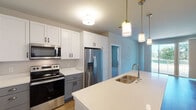 This well-appointed single-floor residence offers a thoughtfully designed open-concept layout that seamlessly connects the kitchen and living areas. The kitchen is a standout feature, showcasing two-tone cabinetry with crisp white upper cabinets and gray lower cabinets, complemented by quartz countertops and a full suite of stainless steel appliances including a French door refrigerator, electric range, and over-the-range microwave. A central island with a double stainless steel sink and elegant pendant lighting serves as both a functional workspace and a natural gathering point. Warm hardwood-style flooring flows throughout the main living areas, adding a sense of continuity and warmth. The living space is generously proportioned, featuring a large closet with double doors and access to an outdoor balcony that invites natural light. The bedrooms are carpeted for comfort and include windows with views of the surrounding greenery. The bathrooms are finished with gray vanities, quartz countertops, and contemporary lighting. The primary bathroom features a glass-enclosed shower, while the secondary bathroom offers a clean, functional design. The overall aesthetic is modern and neutral, providing a bright, move-in-ready environment throughout.