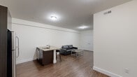 This well-designed 3-bedroom, 3-bathroom single-floor unit makes efficient use of its space through a thoughtful layout that maximizes functionality. The open-concept kitchen and living area serves as the heart of the unit, featuring rich dark cabinetry, stainless steel appliances including a refrigerator, microwave, and range, and granite countertops with a breakfast bar that doubles as a casual dining space. Durable hardwood-style flooring runs throughout the main living areas, complemented by neutral white walls that create a clean, modern aesthetic.

The primary bedroom offers a connected en-suite bathroom and ample closet space, while the two additional bedrooms are finished with plush carpeting and windows that allow natural light and views of the surrounding neighborhood. Each bedroom includes closet storage, with some featuring double-door closets.

All three bathrooms are finished with large-format beige tile and include glass-enclosed walk-in showers with chrome fixtures, wall-mounted sinks, and well-lit vanity mirrors, lending a sleek and contemporary feel. A central hallway connects the private bedroom wing to the main living area. Throughout the unit, the consistent use of neutral tones and modern finishes creates a cohesive and practical living environment.