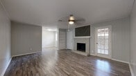 Located at 8623 Starcrest Dr in San Antonio, TX, this single-story, 3-bedroom, 3-bathroom home offers a well-organized layout across a comfortable footprint. The living room serves as the heart of the home, anchored by a classic brick fireplace with a stylish herringbone wood accent panel above it. Built-in shelving flanks the fireplace, and a ceiling fan adds comfort overhead. Wood-look plank flooring runs throughout, lending a cohesive, modern feel to each room. The kitchen features white cabinetry, granite countertops, a mosaic tile backsplash, and stainless and black appliances, including a full-size refrigerator and range. The spacious primary bedroom includes a ceiling fan, natural light from a window, and direct access to an en suite bathroom with a granite vanity. The additional bedrooms each feature wood-look flooring, ample closet space — including double sliding-door closets — and neutral-toned walls, with one room showcasing a distinctive shiplap accent wall. The three bathrooms include tub-shower combinations with white subway tile surround and accessibility grab bars. Textured ceilings are present throughout. A patio provides outdoor access, completing this functional and comfortable San Antonio home.