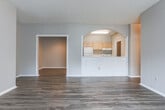 This single-floor residence in Macon, Georgia offers a well-organized layout with a variety of functional spaces throughout. The interior is characterized by consistent wood-look plank flooring in the common areas, providing a cohesive and easy-to-maintain foundation. Neutral gray walls throughout create a clean, understated backdrop adaptable to a range of furnishing styles.

The entry hallway features a distinctive arched opening with decorative column detailing, offering a subtle architectural accent that leads toward the main living areas. The living room is generously sized, with a sliding glass door fitted with vertical blinds that allows natural light to fill the space. A textured ceiling is present throughout the unit.

The kitchen is laid out in a galley configuration, equipped with light wood cabinetry, white appliances including a range and refrigerator, a double sink, and a pass-through window. A dedicated pantry or utility closet is accessible directly from the kitchen, and a separate laundry area with upper cabinetry provides added convenience.

Bedrooms are carpeted for comfort, each offering ceiling fans and access to closet space. One bedroom includes a notably spacious walk-in closet with dual hanging rods. The bathroom features wood-look flooring, a tub-shower combination with tiled surround, a vanity with wood cabinetry, and a tall storage cabinet.