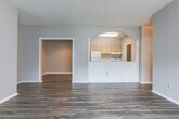 This single-floor residence in Macon, Georgia offers a well-organized layout with a variety of functional spaces throughout. The interior is characterized by consistent wood-look plank flooring in the common areas, providing a cohesive and easy-to-maintain foundation. Neutral gray walls throughout create a clean, understated backdrop adaptable to a range of furnishing styles.

The entry hallway features a distinctive arched opening with decorative column detailing, offering a subtle architectural accent that leads toward the main living areas. The living room is generously sized, with a sliding glass door fitted with vertical blinds that allows natural light to fill the space. A textured ceiling is present throughout the unit.

The kitchen is laid out in a galley configuration, equipped with light wood cabinetry, white appliances including a range and refrigerator, a double sink, and a pass-through window. A dedicated pantry or utility closet is accessible directly from the kitchen, and a separate laundry area with upper cabinetry provides added convenience.

Bedrooms are carpeted for comfort, each offering ceiling fans and access to closet space. One bedroom includes a notably spacious walk-in closet with dual hanging rods. The bathroom features wood-look flooring, a tub-shower combination with tiled surround, a vanity with wood cabinetry, and a tall storage cabinet.