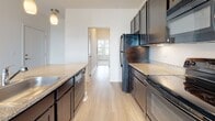 Located in the South Junction neighborhood of Memphis, Tennessee, this single-floor residence offers a clean, modern aesthetic throughout its thoughtfully designed layout. The open-concept living area is finished with light wood-tone flooring that extends seamlessly from the main living space into the kitchen, creating a cohesive and expansive feel. Pendant lighting above the kitchen peninsula adds warmth to the area.

The kitchen is well-equipped with dark espresso cabinetry, granite countertops, and a full suite of black appliances, including a refrigerator, range, microwave, and dishwasher. The galley-style layout maximizes efficiency while the peninsula provides additional workspace and a casual dining option.

The bedrooms feature neutral carpet, ceiling fans, and windows fitted with blinds that bring in natural light and offer views of the surrounding neighborhood. The primary bedroom connects directly to a full bathroom with dark cabinetry, granite countertops, and a shower-tub combination, as well as a spacious walk-in closet outfitted with multi-tiered wire shelving for ample storage. A second full bathroom mirrors the same finishes, maintaining design consistency throughout. The overall palette of crisp white walls and warm wood tones creates a bright, welcoming environment.