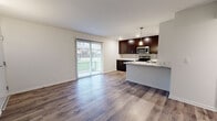 This 2-bedroom, 1-bathroom residence offers a clean, modern aesthetic throughout its single-floor layout. The open-concept living and kitchen area serves as the heart of the home, featuring durable wood-look flooring that extends throughout the main living spaces. A sliding glass door fills the living room with natural light and provides direct access to an outdoor area, creating a seamless indoor-outdoor connection.

The kitchen is a standout feature, equipped with rich dark cabinetry, stainless steel appliances including a refrigerator, range, and microwave, and a peninsula topped with a striking marble-look countertop. A pendant light fixture above the peninsula adds a modern touch, while a tile backsplash completes the polished look.

Both bedrooms are carpeted for comfort and feature ceiling fans with lighting. The primary bedroom is a generously sized retreat, while the second bedroom offers a comfortable and versatile space. A dedicated closet provides additional storage.

The bathroom is elegantly appointed with large-format marble-style tile surrounding the tub and shower, a dark vanity with ample drawer storage, and wood-look flooring. An entry hallway with wall sconce lighting provides a welcoming transition into the living area, completing this well-designed residence.