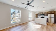 Located at 1410 Breedlove Ln in Indianapolis, IN, this thoughtfully designed single-floor unit offers a clean, contemporary aesthetic throughout. The open-concept kitchen and living area serves as the heart of the space, where light hardwood flooring, neutral warm-toned walls, and multiple large windows work together to create a bright and welcoming atmosphere. Views of the surrounding community are visible through the generously sized windows, which allow sunlight to pour in throughout the day. A ceiling fan with a sleek matte black finish adds both function and style to the living area.

The kitchen is well-appointed with warm-toned cabinetry, white quartz countertops, and a full suite of stainless steel appliances including a refrigerator, range, and microwave. A central island with an undermount sink and a matte black faucet provides additional prep space and serves as a natural focal point, illuminated by modern glass pendant lights overhead.

The bathroom features a clean, contemporary design with a gray-toned vanity, white countertop, a mirrored medicine cabinet, and a full tub-shower combination accented with matte black hardware. A dedicated utility room with stacked laundry adds practical convenience. The additional room offers a flexible, light-filled space with hardwood flooring and a ceiling fan.