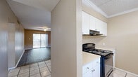 This 2-bedroom, 1-bathroom residence in Tampa, Florida offers a practical and comfortable single-floor layout. The open-concept living room is a welcoming space, featuring wood-look flooring, a ceiling fan with light fixture, and a sliding glass door that opens to a private balcony, allowing natural light to fill the room. The living area flows seamlessly into the kitchen, which is equipped with black appliances including an electric range, refrigerator, and dishwasher, complemented by white cabinetry with ample storage, light countertops, crown molding, and tile flooring. A pendant light over the kitchen pass-through adds a subtle design touch. Both bedrooms are carpeted and finished with neutral warm-toned walls and ceiling fans. The generously sized primary bedroom offers a comfortable retreat, while the second bedroom provides flexibility for guests or a home office. The full bathroom features tile flooring and a shower/tub combo. Two hallways connect the living spaces to the private quarters, and a dedicated closet provides additional storage. The textured ceilings are consistent throughout, adding character to this well-organized Tampa residence.