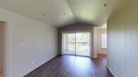 This single-story residence offers a well-designed layout across two bedrooms and one bathroom. The living area immediately captures attention with its vaulted ceiling that amplifies the sense of space, dark hardwood-style flooring, and a large sliding glass door fitted with vertical blinds that invites natural light and provides outdoor views. An additional window near the entry further brightens the area.

The galley-style kitchen is outfitted with dark espresso cabinetry, white countertops, stainless steel appliances including a refrigerator, range, microwave, and dishwasher, along with hardwood-style flooring and a window above the sink for natural light.

The bathroom features a long vanity with dual sinks, dark cabinetry, white countertops, a well-lit mirror, and a separate tub-shower combination, all complemented by hardwood-style flooring. Both bedrooms are carpeted for comfort, each equipped with a ceiling fan and natural light provided by windows with blinds. One bedroom includes multiple closet doors, adding practical storage. Neutral wall tones throughout contribute to a clean, cohesive ambiance.