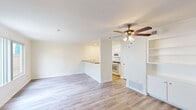 Located at 16900 Algonquin St in Huntington Beach, California, this two-story, 2-bedroom, 1-bathroom home is thoughtfully laid out across two evenly divided floors. The main level features a bright, open living area with light-toned hardwood flooring, a ceiling fan with integrated lighting, and a built-in shelving and cabinet unit flanking a carpeted staircase to the upper level. The entry foyer is clean and welcoming, with the same warm wood flooring flowing throughout. The semi-open kitchen is appointed with white cabinetry, granite-style countertops, a double basin sink, a gas range, and an over-the-range microwave, with a peninsula counter connecting it to the living area. Upstairs, both bedrooms are carpeted and include ceiling fans. The primary bedroom offers a generous footprint with a walk-in closet, while the secondary bedroom features a wide window that brings in natural light. The full bathroom is finished with a tub-shower combination, chrome fixtures, a granite-topped vanity, and wood-style flooring. A dedicated closet adds additional storage. The home's clean, neutral palette and functional layout make it a practical and comfortable residence near the Southern California coast.