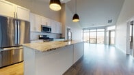 Located at 3600 S Point Rd in Verona, Wisconsin, this single-floor home showcases a contemporary design with clean lines, neutral tones, and thoughtful finishes throughout. The open-concept layout connects the kitchen and living area seamlessly, creating a spacious and airy atmosphere enhanced by soaring vaulted ceilings.

The kitchen is a standout feature, equipped with white shaker-style cabinetry, a classic subway tile backsplash, and a large central island topped with striking granite countertops. Stainless steel appliances, including a gas range, microwave, and refrigerator, add a sleek, functional element, while stylish pendant lights overhead provide focused illumination. A wall of large windows in the adjacent living area floods the space with natural light and offers views of the surrounding neighborhood.

The bathrooms are finished with granite-topped white vanities, wood-look flooring, and large mirrors. The primary bath features a dual-sink vanity for added convenience. Bedrooms are carpeted and include tray ceiling details and windows that bring in natural light. A dedicated laundry area with a full-size washer and dryer rounds out the home's practical amenities. Wood-look flooring flows throughout the main living areas, contributing to the home's warm, modern aesthetic.