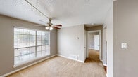 Located at 1100 Willow Springs Rd in Killeen, Texas, this single-floor, 2-bedroom, 1-bathroom home offers a functional and efficient layout. Neutral taupe walls, white baseboards, and wall-to-wall carpeting create a consistent, understated aesthetic throughout the living and bedroom spaces.

The living room provides a comfortable gathering area with a ceiling fan fitted with a light fixture and a window with blinds that allows natural light to filter in. A hallway connects the living area to the rest of the home, with floor vents ensuring climate control throughout.

The kitchen follows a galley-style configuration with warm hardwood flooring, white cabinetry, grey laminate countertops, a double-basin stainless steel sink, and black appliances including a range, dishwasher, and refrigerator — offering practical storage and workspace.

The primary bedroom is a well-proportioned space featuring a ceiling fan with lighting and a window with blinds. The second bedroom also includes a ceiling fan, carpeted flooring, and a closet with a hanging rod for storage.

The bathroom is clean and straightforward, featuring a full-size tub and shower combo with white tile surround and chrome fixtures. Textured ceilings are present throughout, adding a familiar residential character to the home.