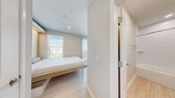 Located at 1116 W Carmen St in Tampa, FL, this compact and thoughtfully designed studio unit offers a smart, modern layout that maximizes every square foot. The space features light wood-tone flooring throughout, neutral warm-white walls, and recessed lighting that contribute to a bright and cohesive aesthetic.

The sleeping area is anchored by a built-in Murphy bed with an integrated wood-paneled surround and soft underlighting, providing both functionality and a clean, contemporary look. Two windows with horizontal blinds and a vertical blind panel allow ample natural light to filter in, with views of the surrounding Tampa neighborhood.

The kitchen is efficiently appointed with stainless steel appliances, including a full-size refrigerator, electric range with smooth cooktop, over-range microwave, and a deep single-basin stainless steel sink with a professional-style pull-down faucet. Light wood cabinetry and a white quartz-style countertop keep the kitchen feeling open and modern.

The bathroom is neatly finished with wood-look tile flooring, a full-size soaking tub with shower, a white tile surround, and a vanity with under-mount sink and wood-toned cabinetry. Recessed lighting provides clear, functional illumination throughout. This well-appointed studio is ideal for those seeking a streamlined, low-maintenance living space in a vibrant Tampa location.