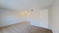 This single-floor unit offers a straightforward, functional layout with clearly defined living, sleeping, kitchen, and bathroom areas. The living space is generously proportioned, featuring neutral gray walls, plush wall-to-wall carpeting, and a textured ceiling. A distinctive arched window allows natural light to fill the room, complementing the front entry door fitted with a deadbolt for added security.

The bedroom area mirrors the living space in its clean, understated aesthetic, with matching carpet, neutral walls, a ceiling fan with an integrated light fixture, and a window that brings in additional natural light. A closet with a standard door provides convenient storage.

The kitchen is compact yet efficiently arranged, featuring white cabinetry, a laminate countertop with a stainless steel sink, wood-look vinyl flooring, and black appliances including a gas range and a full-size refrigerator. Overhead cabinetry provides ample storage space.

The bathroom includes a full-size soaking tub with a tiled surround in warm neutral tones, a showerhead, and tile flooring, offering a practical and clean bathing environment. Throughout the unit, a consistent neutral color palette and textured ceilings contribute to a cohesive, understated ambiance.