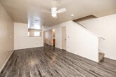 This two-story home offers a practical and well-organized layout across two floors, accommodating three bedrooms and three full bathrooms. The main level features an open-plan kitchen and living area finished with durable wood-look laminate flooring throughout. The kitchen is equipped with warm honey-toned wood cabinetry, white countertops, and a full suite of black appliances including a refrigerator, range, microwave, and dishwasher. A window above the sink allows natural light into the space, and a exterior-facing door provides convenient access. The living area is highlighted by a ceiling fan with integrated lighting and a textured ceiling, with a staircase leading to the upper level. A dedicated laundry room on the main floor houses a full-size washer and dryer set with built-in shelving above and a large window that brings in natural light. The upper floor hosts the bedrooms, which feature plush carpeting and windows that allow ample natural light. The primary bedroom offers a comfortable amount of space with a sliding closet. The three bathrooms are consistently finished with wood-toned vanities, stone-look countertops, and shower-tub combinations. Throughout, the home maintains a clean, neutral palette.
