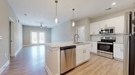 Located at 8000 Carlow Dr in Kernersville, NC, this well-appointed single-floor residence offers three bedrooms and two bathrooms across a thoughtfully designed layout. The open-concept kitchen and living area serves as the heart of the home, anchored by a central island with a granite countertop, an undermount sink, and pendant lighting above. White shaker cabinetry, a classic subway tile backsplash, and a full suite of stainless steel appliances — including a refrigerator, range, microwave, and dishwasher — complete the kitchen. The living area extends naturally from the kitchen, featuring light hardwood-style flooring, a ceiling fan, and French doors that invite natural light and outdoor access. The primary bedroom offers a comfortable footprint with ceiling fan and carpeted flooring, while the additional bedrooms also feature carpet and windows with natural light. Two closets provide practical storage throughout. The primary bathroom showcases a dual-sink granite vanity with white cabinetry, brushed nickel fixtures, and a tiled walk-in shower. Neutral tones, clean white trim, and consistent finishes throughout create a cohesive, move-in-ready aesthetic that is both functional and inviting.