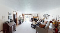This single-floor home offers a thoughtfully designed layout with a comfortable and functional flow throughout. The spacious living room serves as the heart of the home, centered around a tile-surround fireplace with a warm wood mantle and large mirror above. Plush carpeting, neutral walls, and a sliding glass door that invites natural light and outdoor views contribute to the room's welcoming ambiance.

The kitchen is well-equipped with rich oak cabinetry extending to the ceiling for generous storage, light-toned countertops, and a full suite of appliances including a dishwasher, range, refrigerator, and built-in microwave. A peninsula with bar seating adds casual dining convenience, while tile flooring grounds the space practically.

Adjacent to the kitchen, the dining area features carpeted floors and a ceiling fan with light fixture, offering a comfortable setting for everyday meals. The bedrooms are carpeted and bright, each with ceiling fans and natural light from windows with blinds. The primary bedroom benefits from dual closets, providing exceptional storage capacity.

The bathroom includes oak cabinetry, a vanity with sink, and vinyl tile flooring, delivering a clean and functional space. Throughout the home, warm wood tones, neutral walls, and consistent finishes create a cohesive and inviting atmosphere.