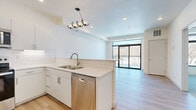 Located at 1247 Range St in Mankato, MN, this modern one-bedroom, one-bathroom unit offers a thoughtfully designed open-concept layout with clean, contemporary finishes throughout. Light-toned hardwood-style flooring runs through the main living areas, lending a bright and cohesive feel to the space.

The kitchen and living room share an open, flowing layout anchored by a peninsula with white quartz countertops and classic subway tile backsplash. The kitchen is fully equipped with stainless steel appliances — including a French door refrigerator, electric range, over-the-range microwave, and dishwasher — paired with crisp white cabinetry and a double basin sink. A stylish multi-bulb pendant light adds a decorative focal point above the peninsula. The living area opens directly onto a private balcony through large sliding glass doors framed in black, offering outdoor views of surrounding trees and natural scenery.

The bedroom is a comfortable, well-proportioned retreat featuring plush carpet, a ceiling fan, and a large black-framed window that fills the room with natural light. The bathroom is finished with tile flooring, a walk-in shower, white vanity with quartz countertop, and a large mirror. A dedicated utility room completes the unit's functional layout.