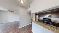 This thoughtfully designed single-story residence offers 1 bedroom and 2 full bathrooms within a comfortable and efficiently arranged floor plan. The open-concept kitchen and living area serves as the heart of the home, featuring rich dark-cabinetry, granite stone countertops, a breakfast bar peninsula, and stainless steel appliances including a refrigerator, range, and built-in microwave. Hardwood-style flooring runs throughout the main living areas, complementing the neutral light-gray walls and clean white trim. The living room is bright and airy, benefiting from a ceiling fan and sliding glass doors that open to an outdoor patio, allowing an abundance of natural light to fill the space. The spacious primary bedroom is finished with plush carpeting, a ceiling fan, a large window with outdoor views, and access to a generous walk-in closet with built-in shelving. Both bathrooms are well-appointed, with one featuring a granite vanity, dark wood cabinetry, a large wall mirror, and a tiled shower-tub combination. A dedicated hallway provides access to a closet and in-unit laundry connections. The layout is completed by a practical hallway connecting all areas seamlessly, offering a functional and comfortable living environment throughout.