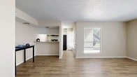 Located in Arlington, Texas, this single-story residence offers a thoughtfully designed layout encompassing one bedroom and one bathroom. The open-concept living room serves as the heart of the home, bathed in natural light from two large windows dressed with horizontal blinds. Wood-look tile flooring flows seamlessly throughout the main living and kitchen areas, creating a cohesive and easy-to-maintain foundation.

The kitchen is defined by a pass-through counter with a granite-style surface that opens to the living space, promoting an interactive and connected feel. White cabinetry lines the upper portion of the kitchen wall, complemented by a black refrigerator, range, and an overhead ventilation hood. A textured popcorn ceiling adds character throughout the home.

The spacious primary bedroom features plush wall-to-wall carpeting, a mirrored sliding closet, and a dedicated window that allows natural light to filter in. Neutral warm-toned walls carry throughout the entire residence, lending a calm and cohesive aesthetic. A hallway connects the bedroom to the full bathroom, which showcases a granite-topped vanity with white cabinetry. The bathroom also provides access to a walk-in closet area, adding practical storage to the overall floor plan.