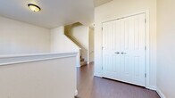 Located at 1855 Vaness St in South Bend, Indiana, this multi-floor home spans three levels and offers a practical, well-organized layout ideal for comfortable living. The main living level features an open-concept kitchen and living room area with warm hardwood-style flooring throughout. The kitchen is outfitted with rich oak cabinetry, light countertops, a central island with bar seating, and stainless steel appliances including a refrigerator, range, microwave, and dishwasher. The adjacent living room is bright and inviting, with a large window that allows natural light to fill the space. A half bathroom on this level adds convenience for guests. Staircases connect all three floors, with hallways providing smooth circulation between rooms. The upper floors house four well-proportioned bedrooms, each with carpeted floors and ample closet space. The generously sized primary bedroom features vaulted ceilings, a walk-in closet, and its own private bathroom. Additional full bathrooms serve the remaining bedrooms, each featuring a tub-shower combination, wood-toned vanity cabinetry, and hardwood-style flooring. The home's neutral color palette, clean lines, and consistent finishes throughout create a cohesive and functional living environment.