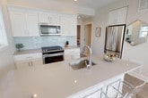 Located at 262 Indian Head Rd in Kings Park, NY, this single-floor home offers a thoughtfully designed layout with modern finishes throughout. The open-concept kitchen is a standout feature, showcasing crisp white shaker cabinetry, a glass subway tile backsplash, quartz countertops, and a spacious island with seating for several. Stainless steel appliances, including a gas range, built-in microwave, and French door refrigerator, complete this well-appointed space. Natural light pours in through multiple windows, enhancing the home's bright, airy aesthetic. The living area provides a comfortable gathering space with recessed lighting and large windows offering views of the surrounding neighborhood. Multiple bedrooms are finished with neutral tones, hardwood-style flooring, ceiling fans, and ample closet space, creating restful retreats. The bathrooms are elegantly appointed with light tile flooring, a stylish gray vanity with undermount sink, a tub-shower combination, and a separate glass-enclosed walk-in shower with subway tile surround. Throughout the home, a cohesive palette of soft grays and whites, recessed lighting, and light wood-tone flooring creates a clean, contemporary ambiance that is both inviting and functional.