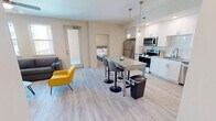 This contemporary 880 square foot apartment offers a thoughtfully designed living space with two bedrooms and two bathrooms. The open-concept layout seamlessly integrates the kitchen, dining, and living areas, creating a spacious feel. The kitchen boasts sleek white cabinetry, stainless steel appliances, and a granite countertop that extends to form a dining bar.

The living room is bathed in natural light from large windows and features modern furnishings, including a comfortable grey sofa and a vibrant yellow accent chair. A ceiling fan with integrated lighting enhances comfort and illumination throughout the space.

Both bedrooms are well-proportioned, with the primary bedroom measuring 140 square feet. They feature plush carpeting, ample closet space, and ceiling fans. The bathrooms are elegantly appointed with marble-look tiled showers, granite countertops, and modern fixtures.

Storage is abundant throughout the apartment, with a walk-in closet showcasing adjustable shelving systems. The overall design emphasizes a neutral color palette with light wood-look flooring, creating a bright and airy atmosphere. This efficiently designed apartment combines style and functionality, perfect for modern urban living.