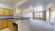 This single-floor residence offers a well-organized layout designed for comfortable everyday living. The open-concept living and dining area is finished with plush carpet and crowned with elegant crown molding, while a decorative pendant light adds a refined touch. A ceiling fan provides year-round comfort, and multiple windows invite generous natural light and outdoor views.

The kitchen connects seamlessly to the living space via a breakfast bar with dark granite-style countertops. Warm honey-toned cabinetry lines the walls, complemented by black appliances including a refrigerator, range, microwave, and dishwasher. Large-format tile flooring provides a clean, durable surface throughout the kitchen.

The bedrooms are carpeted and feature neutral warm-toned walls. Several rooms include sliding glass doors that open directly to a covered balcony, extending the living space outdoors. One bedroom features a built-in closet with shelving, while another includes crown molding and a large window for added brightness.

Two full bathrooms serve the residence, each appointed with warm wood-toned vanity cabinetry, white countertops, a single sink, a large mirror with overhead lighting, and a tub-shower combination. Tile flooring in a parquet-style pattern adds a classic detail to each bathroom. The overall design is functional, clean, and move-in ready.