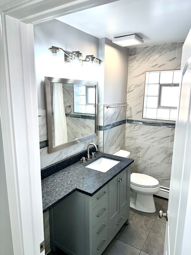 Newly redone full bath with new large counter, Kohler toilet & tiled walls & floor. - 771 56th St